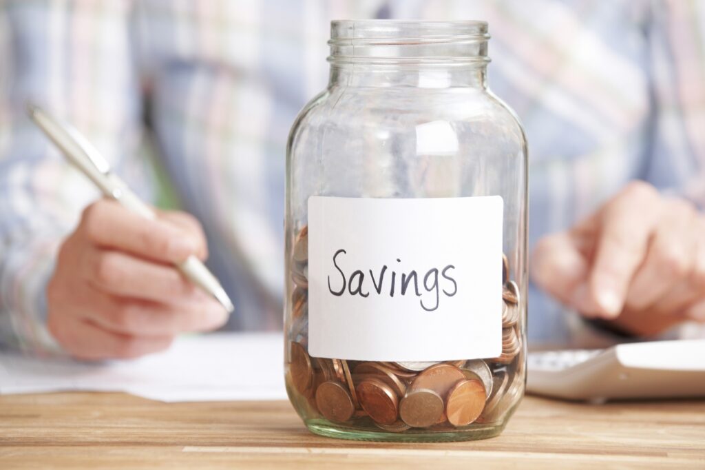 woman calculating budget with savings jar in foreground