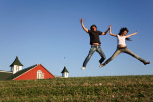 Millennial couple jumping with joy with house as background